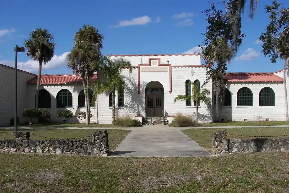 Historic J. Colin English School building with palms and a stone wall in North Fort Myers